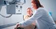 Female patient speaking with doctor during X ray scanning preparation